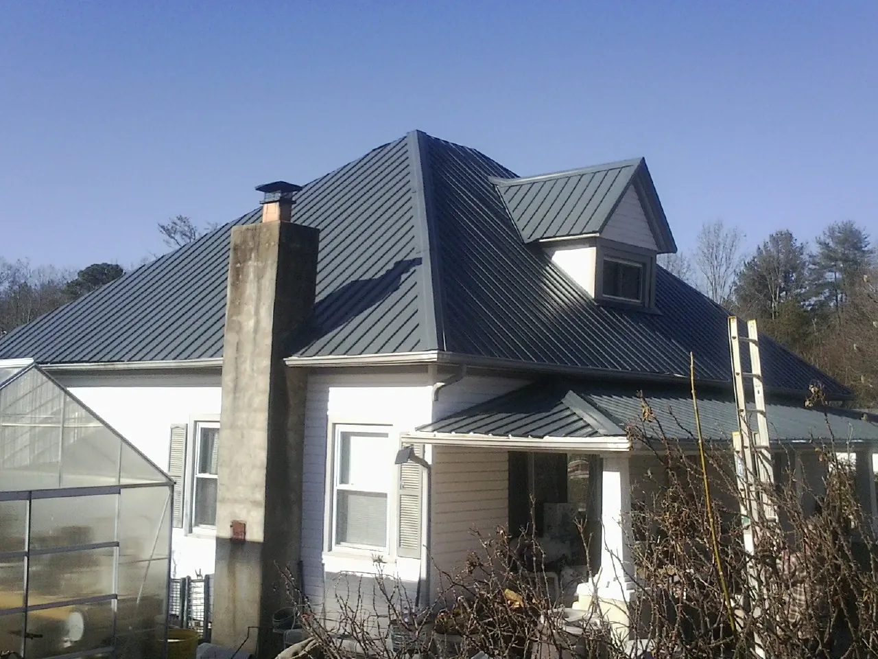 Dark blue standing seam metal roof on a white farmhouse with dormer — Slate & Tile Roof Repair by Roofing Brothers in Butler