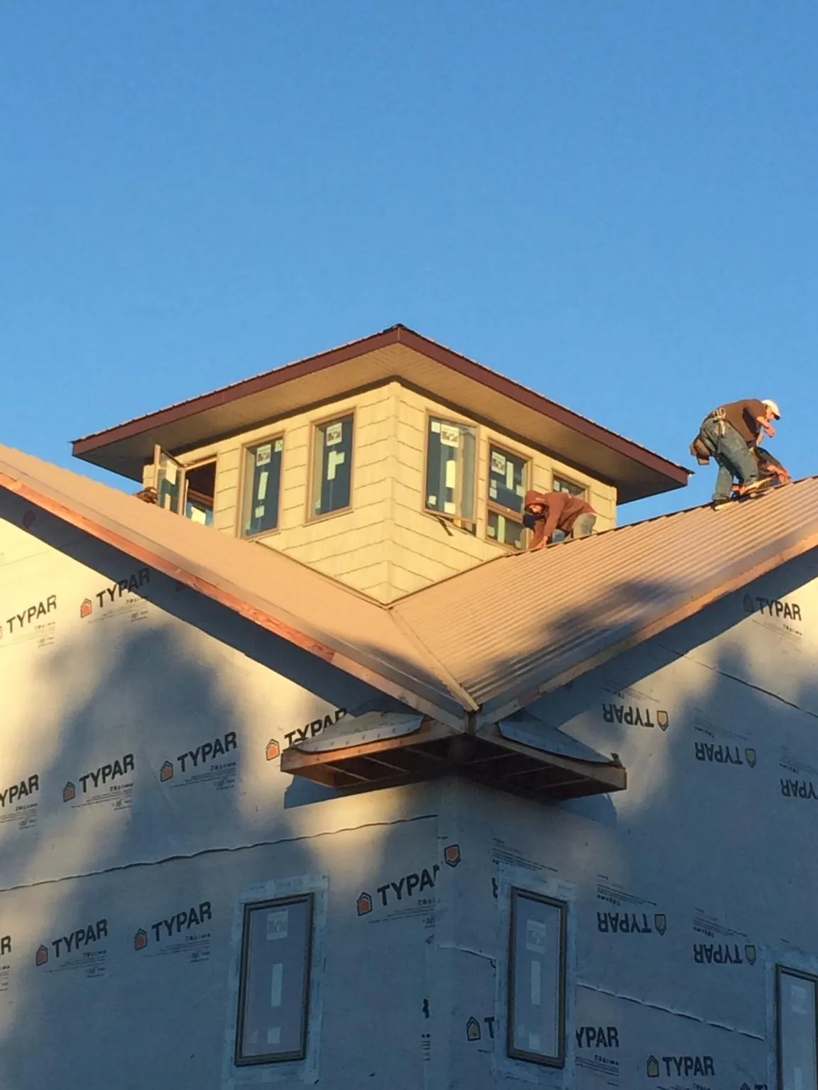 Roofers working around a rooftop cupola on a new metal roof at sunset — Roof Waterproofing in Butler by Roofing Brothers